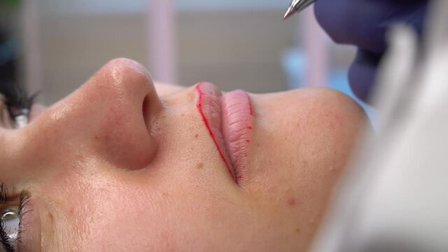 Make up artist makes pencil marks before procedure of permanent lips makeup.