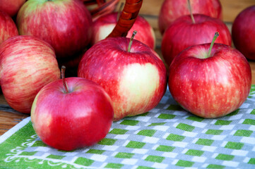 Apples are scattered from the basket onto a green napkin. . High quality photo