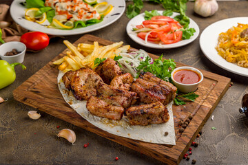 Kebab of pork, steak of salmon on creamy sauce with red caviar, vegetable salad and pilaf with beef side view on brown table