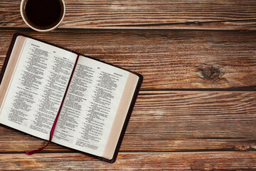 Open Holy Bible Book on wooden table background with a cup of coffee with copy space for text. The...