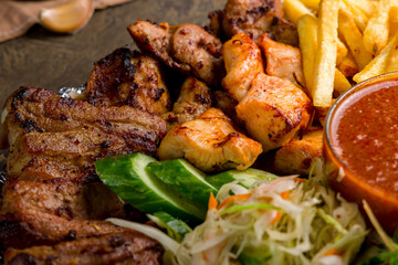 platter of different kebabs, kebab from chicken fillet, kebab of veal, french fries and vegetables with tomato sauce macro close up