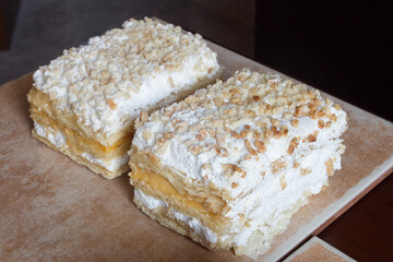 Two traditional dessert portions of Costrada on an artistic modern platter. Dessert of millefeuille with puff pastry dessert, filled with cream and meringue and covered with chopped and icing sugar.