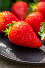 New harvest of ripe red sweet strawberry on farmer fiels and green leaves of strawberry plants close up