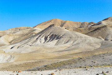 Stone Desert on the West Bank. Judean Desert in clear weather. White sand dunes and blue sky. Stony desert in the spring, green grass. Sand Hills of Judean Mountain, Israel. 