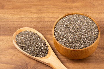 Chia seeds in wooden bowl and wooden spoon.