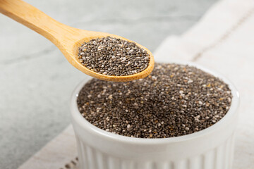 Chia seeds in bowl and wooden spoon on the table.