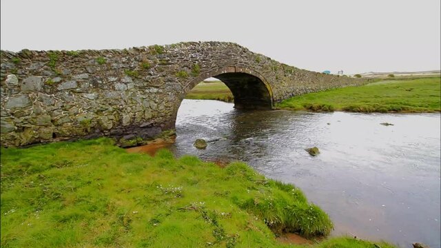 Old hump-backed bridge Pont Pont Aberffraw on Anglesey, Wales UK, wide angle