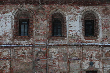 Fototapeta na wymiar Wall of old red brick house with arch windows
