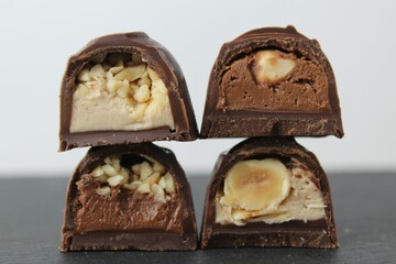 four chocolates in frosted nuts whole crushed peanuts hazelnuts dark light chocolate cream pralines close-up lie on top of each other