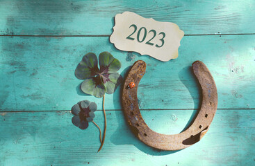 Horseshoe with lucky clover - 2023 greeting card	 horseshoe on wooden background - happy new year greetings, wishes