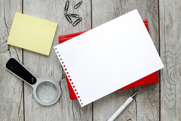 desktop with office accessories, notepad and colorful stickers. Wooden background with copy space for lettering loupe