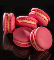 pink macaroons on black background with reflection