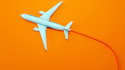 White passenger plane in flight on a beautiful orange background top view, flying with a contrail,...