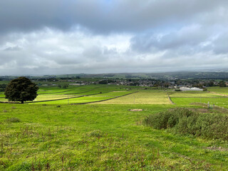 Naklejka premium Extensive rural landscape, with fields, houses, and heavy rain clouds over distant hills near, Allerton, Bradford, UK