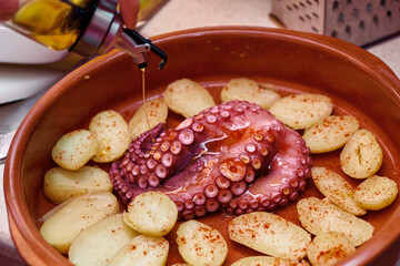 closed shot cooking baked octopus with potatoes, olive oil and paprika typical and healthy food