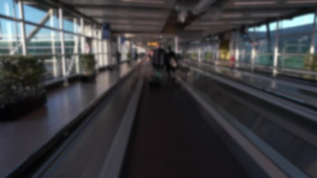 Blurred defocused tracking shot of passengers in magnetic stairs at international Airport. Travelling of people walking in modern terminal lounge gate