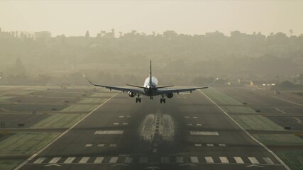 Big commercial plane serving domestic flight as seen from above. Huge aircraft landing on a runway with a cityscape behind. High quality 4k footage - Powered by Adobe