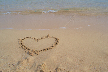 Painted heart on the sandy shore of the sea