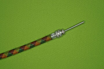 a long colored bicycle hose with a gray metal needle lies on a green table