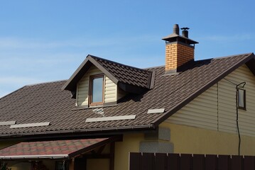 one  attic window on a brown tiled roof of a privat house against a blue sky