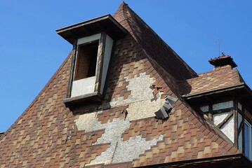 attic of an old abandoned private house  under a brown broken tiled roof against a blue sky