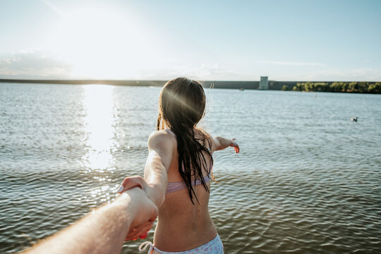 Teen girl holding a hand leading them to a lake