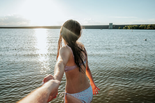Close up of teen girl leading someone into a lake