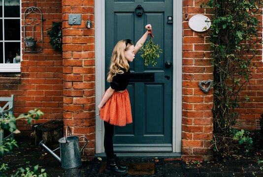 young girl holding mistletoe leaning forward waiting for a kiss