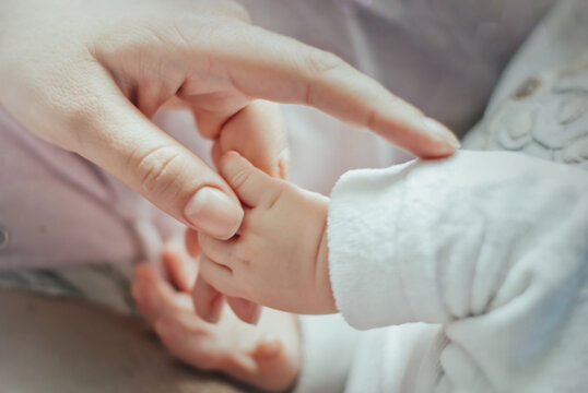 Newborn baby holding mother's hand.