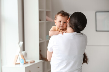 Young mother holding her little baby at home