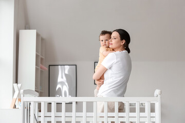 Young mother holding her little baby in bedroom