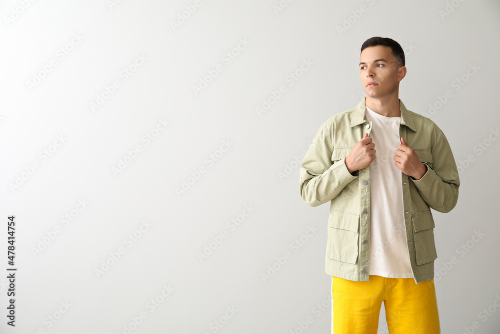 Wall mural Young man in stylish jacket on light background