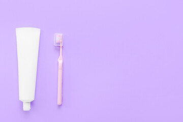 Tube with tooth paste and brush on purple background