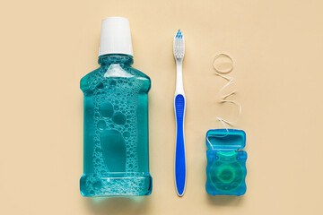 Dental floss, tooth brush and rinse on beige background