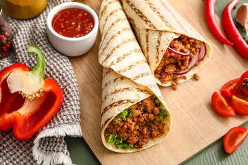 Tasty burritos and sauce on color wooden background