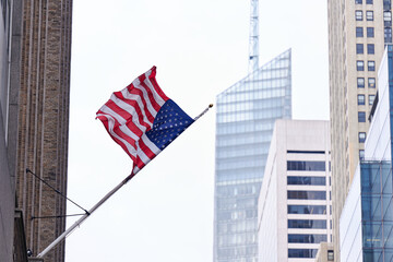 NEW YORK CITY, USA - DECEMBER 10TH 2021: scenes outside Grand Central Terminal. The American flag spread by the wind with Manhattan skyscrapers in the background.