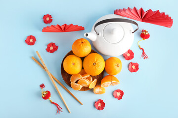 Tasty tangerines with traditional Chinese tea on color background