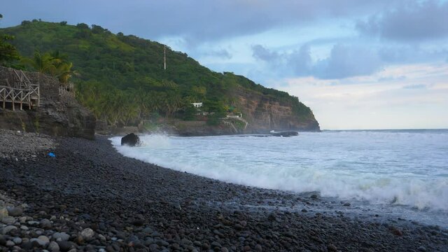 Full shot, waves rushing to the rocky shores on the bitcoin beach in El Salvador, Mexico, scenic view of the cliff and blue sky in the background.