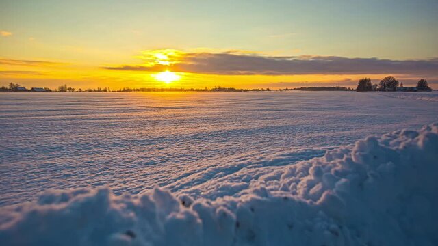 Wide shot of golden sunset at horizon lighting over white winter landscape,time-lapse