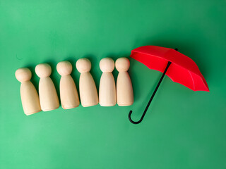 Red umbrella with peg doll arrangement to protect wooden peg doll, plan, save family, prevent risk and crisis, health care and insurance concept.