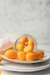 Jar with tasty kumquat fruits on light background