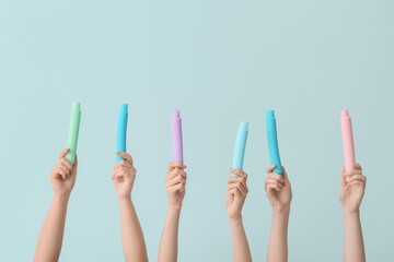 Hands with popular pop tubes on color background