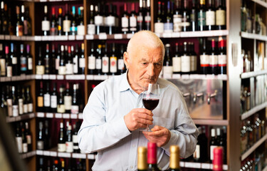 Elderly man smells the quality of red wine. High quality photo