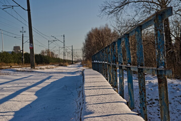 Mostek kolejowy z barierką niebieską w śniegu zimową porą . - obrazy, fototapety, plakaty