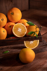Under the dim light, the oranges on the plate are on the wooden table, like oil paintings