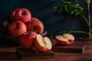 The apples on the plate look like oil paintings under the dim light on the wood grain table