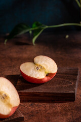The apples on the plate look like oil paintings under the dim light on the wood grain table