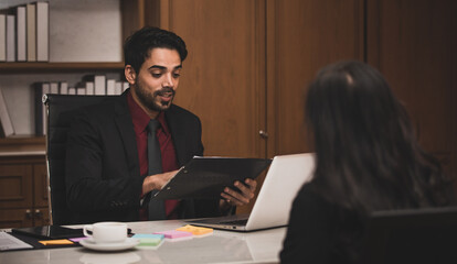 Closeup shot of Millennial Indian Asian professional successful executive bearded male businessman manager entrepreneur in formal suit sitting smiling shaking hands with businesswoman colleague