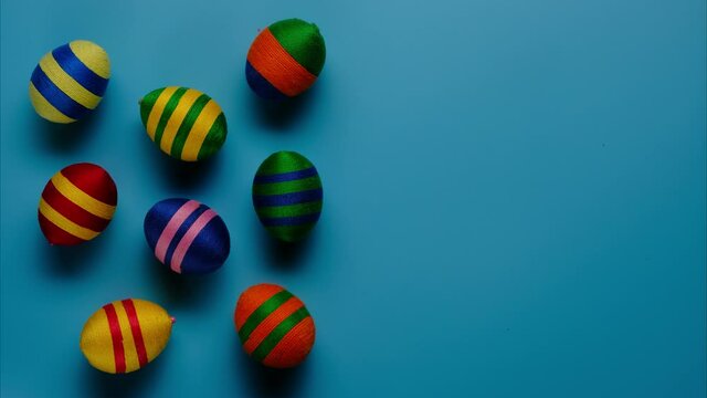 Stop motion animation of colorful easter egg made from threads isolated on blue background. Easter concept.