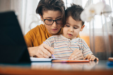 Mom teaching with love his son writing. Family time.